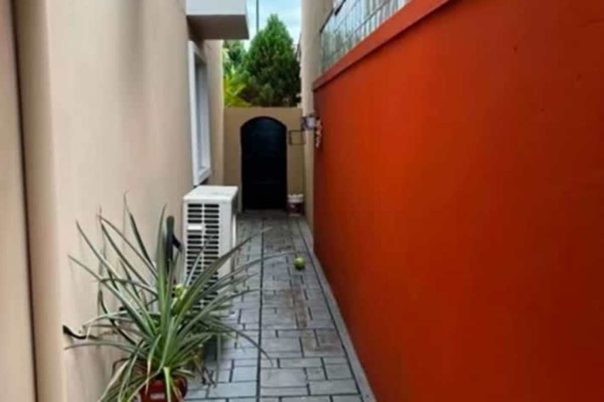 Narrow exterior walkway with arch gate, tiled floor, AC unit in Campo Lindbergh Panama