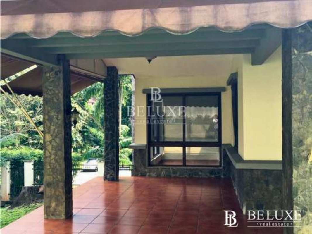 Terracotta tiled covered patio with stone columns garden view Panama home