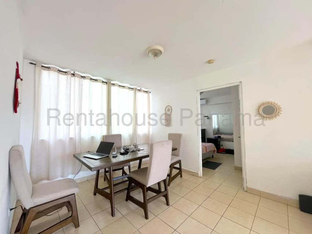 Dining room with beige tiles, window light and simple furnishings in Edison Park apartment