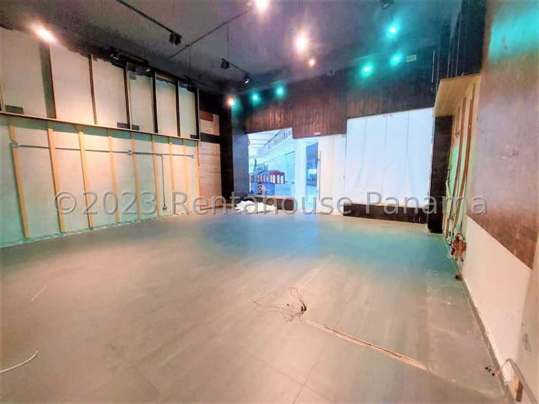Spacious empty interior with unfinished walls, glass door and black ceiling for lease at Albrook Mall Panama
