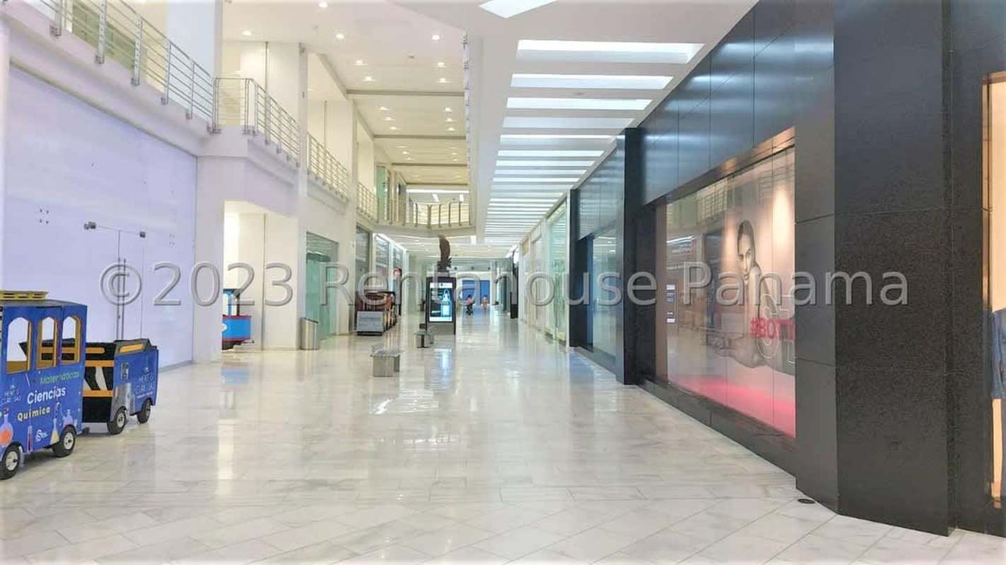 Wide hallway with marble floors, glass storefronts and elevator access at Albrook Mall Panama City