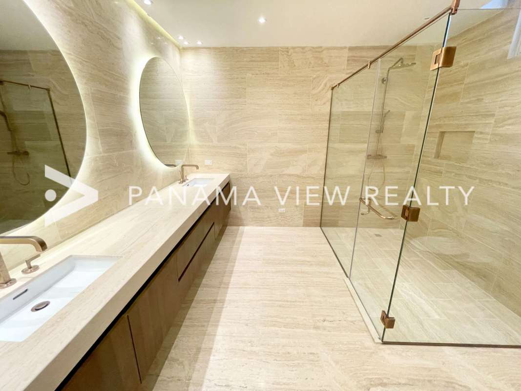 Premium bathroom featuring marble tile, double sink vanity, circular mirrors, walk-in shower in The Towers Panama