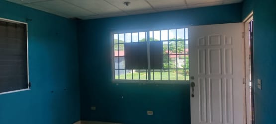 Living area with blue walls white door metal bars window Penonomé house