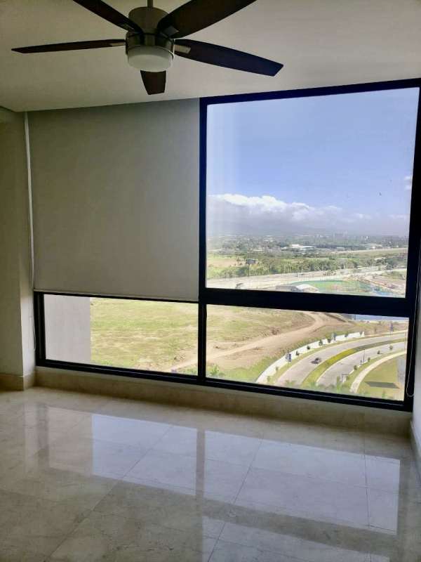 Bright living room with marble floors, large glass sliding doors opening to balcony with skyline and golf view at PH La Vista Santa Maria Panama City