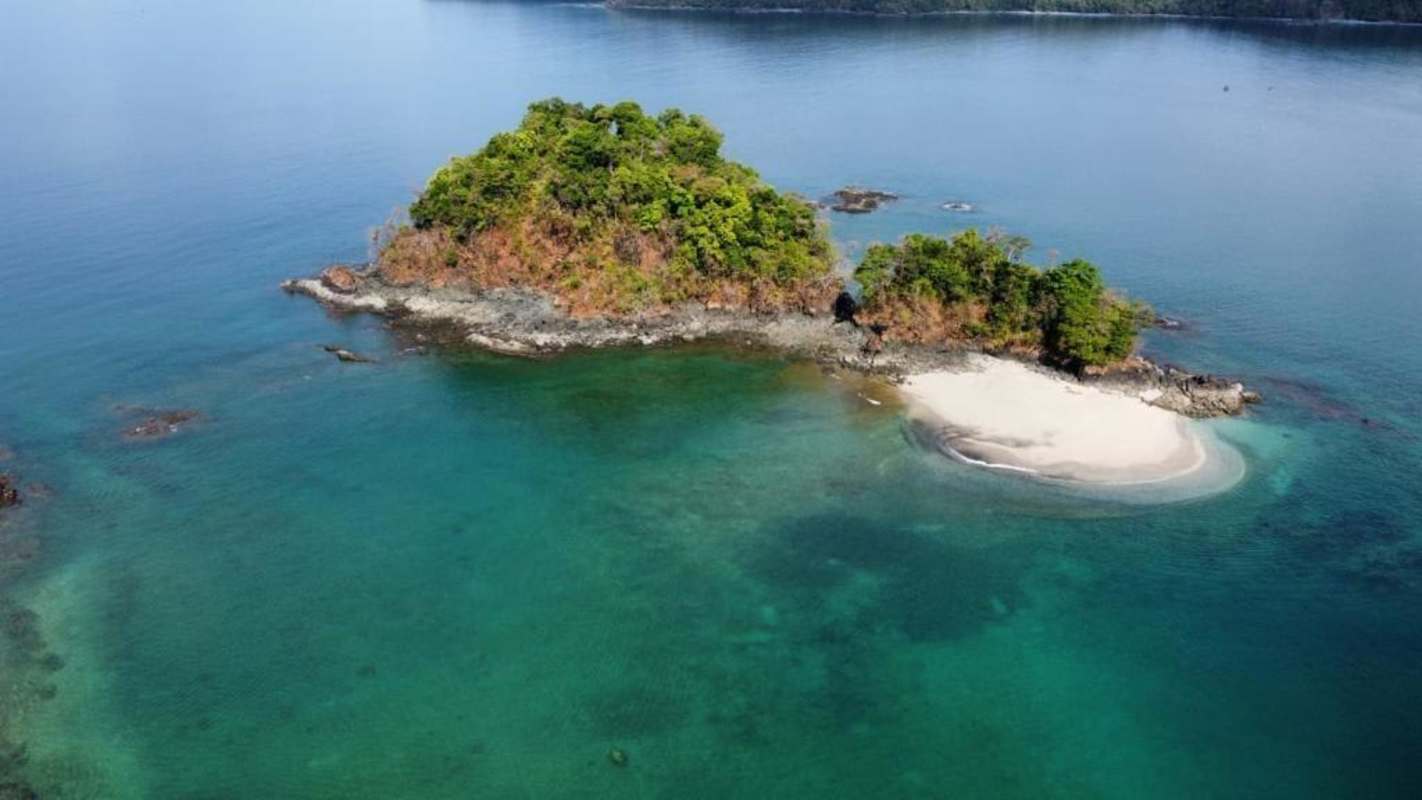 Aerial of lush tropical island with white sand beaches surrounded by blue waters in Panama's Pacific
