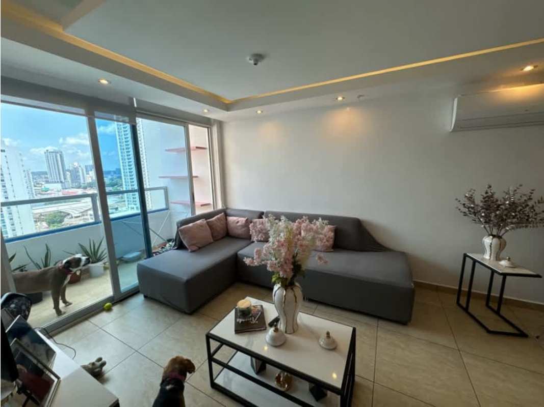 Living room with gray sofa, glass doors to balcony, city skyline views in PH Vista Park Carrasquilla Panama