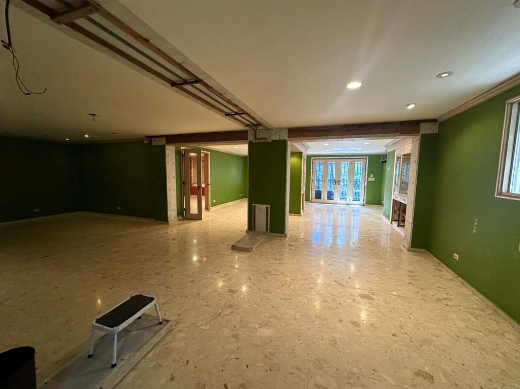Spacious room with green walls, marble flooring, multiple French doors leading outdoors, commercial house Panama City