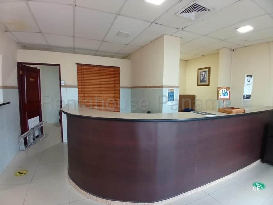 Reception desk area with curved dark wood counter and neutral tile in PH Kamelia Plaza Panama City