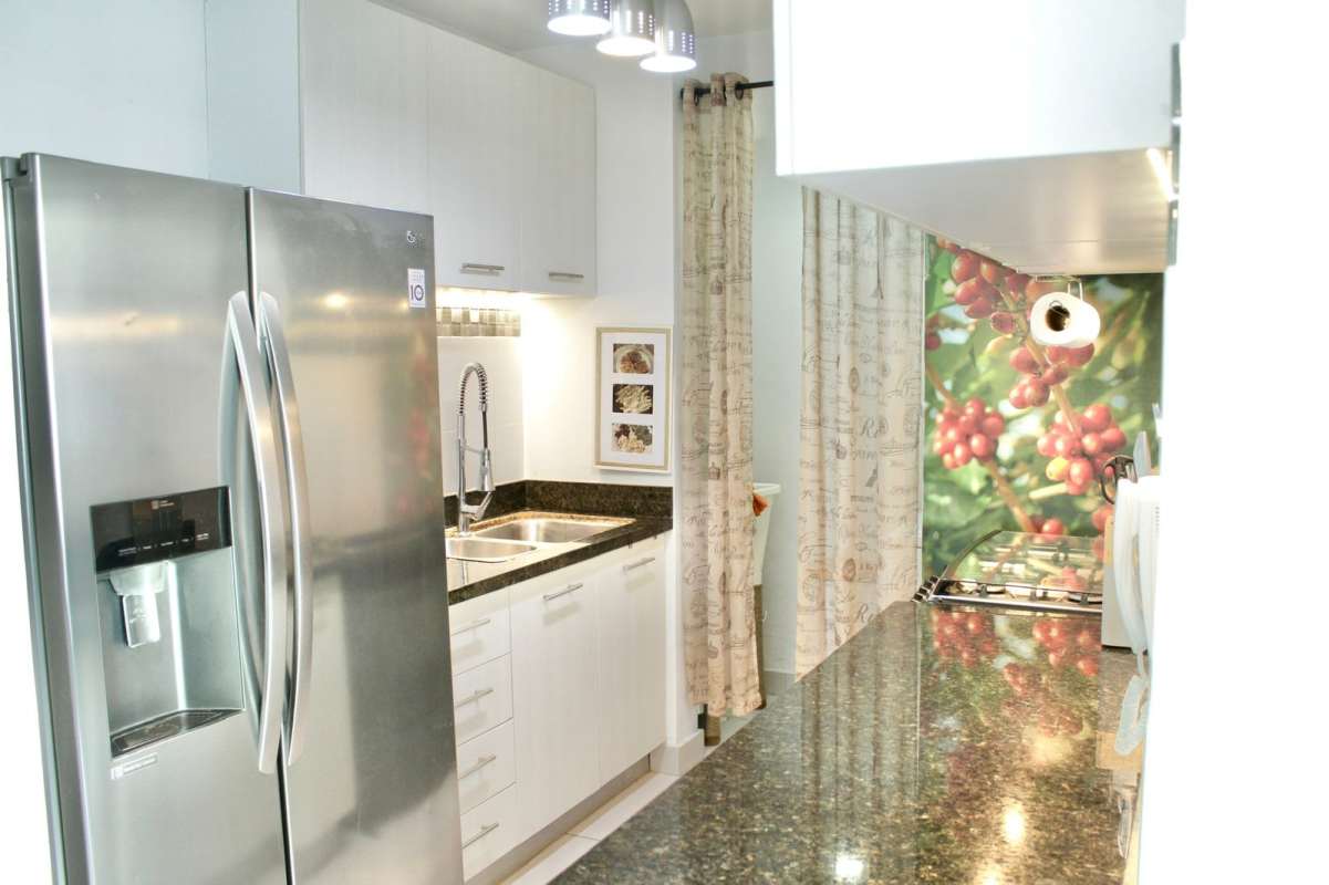 Open kitchen with granite countertops, stainless refrigerator, and modern cabinetry in PH Moderno Panama City