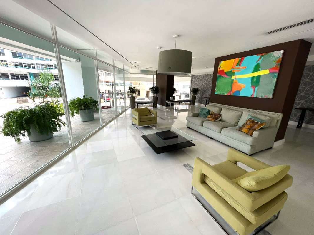 Outdoor swimming pool deck with palm trees, lounge chairs, and skyline view at PH Moderno Panama City