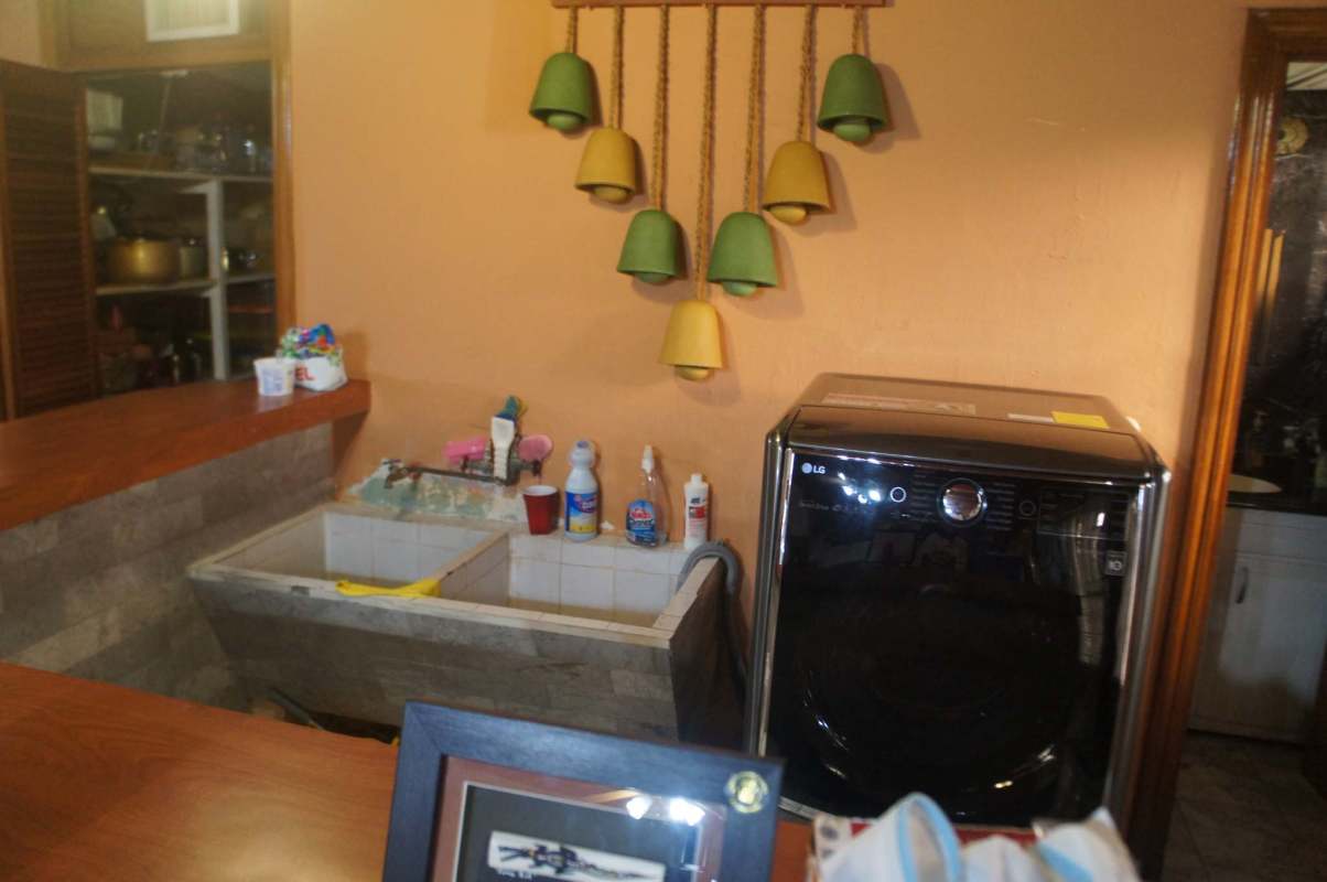 Traditional kitchen with wooden cabinets, granite backsplash, double sink, and appliances in Los Rios home Panama