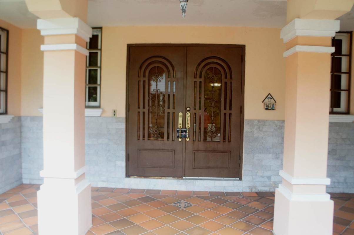 Front facade with arched double doors, peach walls, grey stone half wall and terracotta tile floor Los Rios