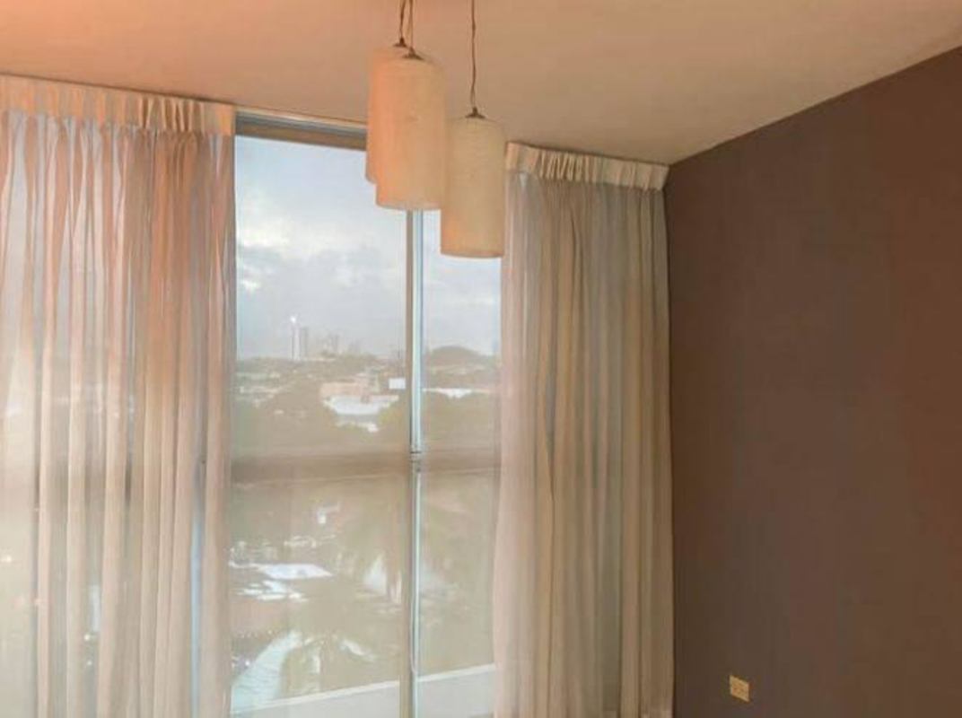 Living room area with large windows, pendant lights and accent wall PH Metro Tower Panama City