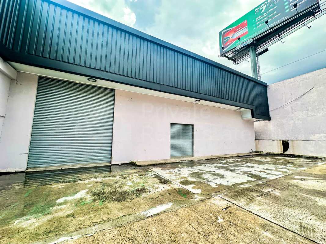 Facade of industrial warehouse with large rolling metal doors and ample driveway in Panama City