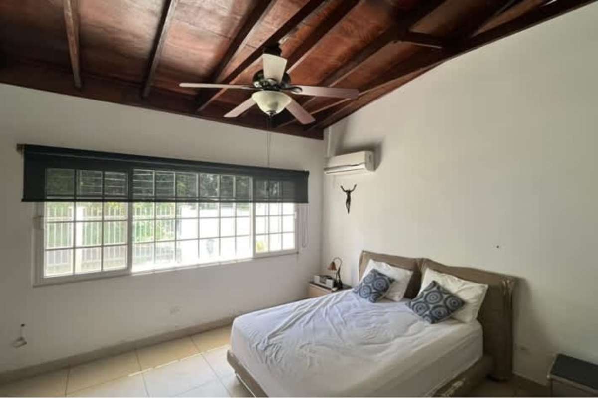 Bedroom with wooden ceiling beams, AC, large window and minimalist decor in house Llanos de Curundú Panama