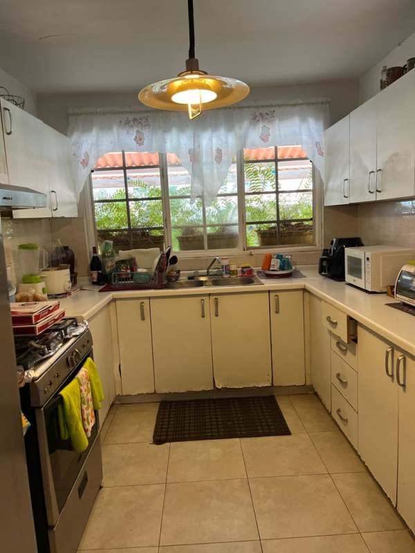 Kitchen space with cabinets and tile floors at house in Brisas del Golf Panama