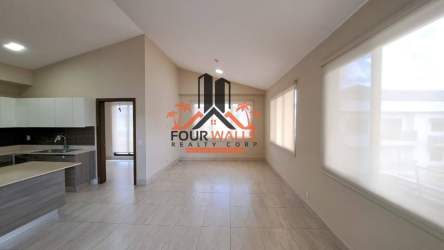 Modern open-plan living room and kitchen with vaulted ceiling and tiled floors in Panama Pacifico condo