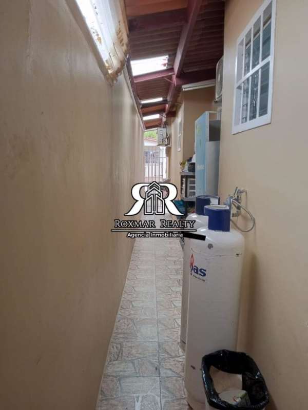 Narrow covered utility corridor with gas cylinders at Brisas del Golf house for sale