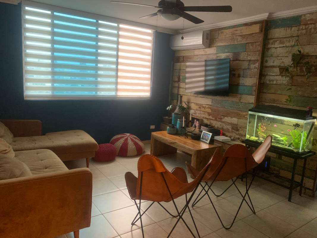 Living room with rustic accent wall, sectional sofa, natural light PH Andros Tower Panama