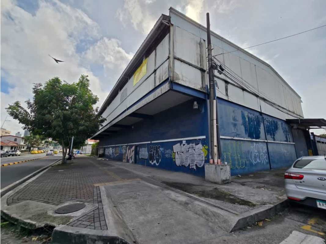 Exterior of large industrial commercial warehouse with blue siding graffiti and parking Panama City