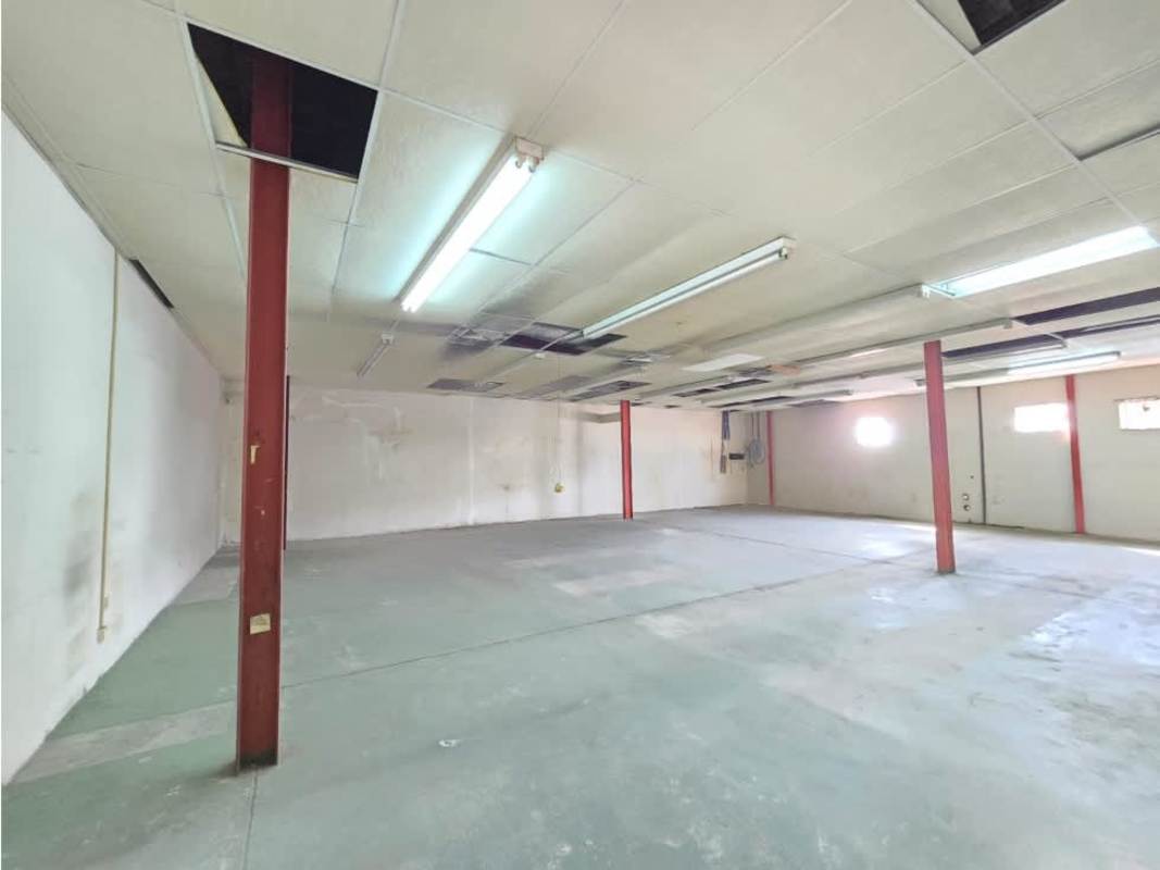 Double height empty warehouse interior steel beams fluorescent lights concrete floor Panama City