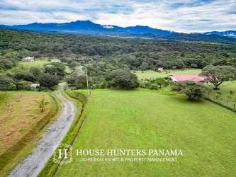 Grassy fenced plot with gravel road lined by lush vegetation and blue skies in Chiriquí highlands Panama