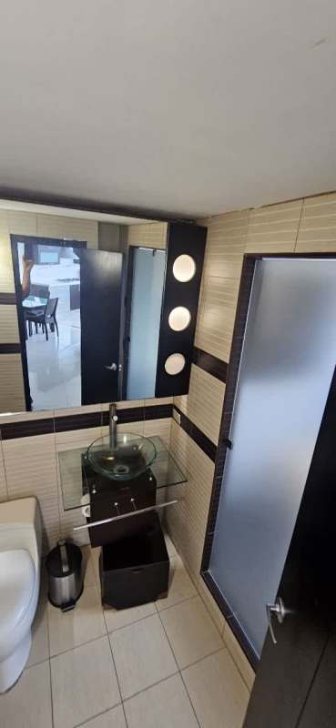 Modern bathroom with glass vessel sink and frosted glass shower door in PH San Miguelito Suites Panama City