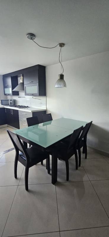 Modern kitchen and dining open layout black cabinets glass table PH San Miguelito Suites