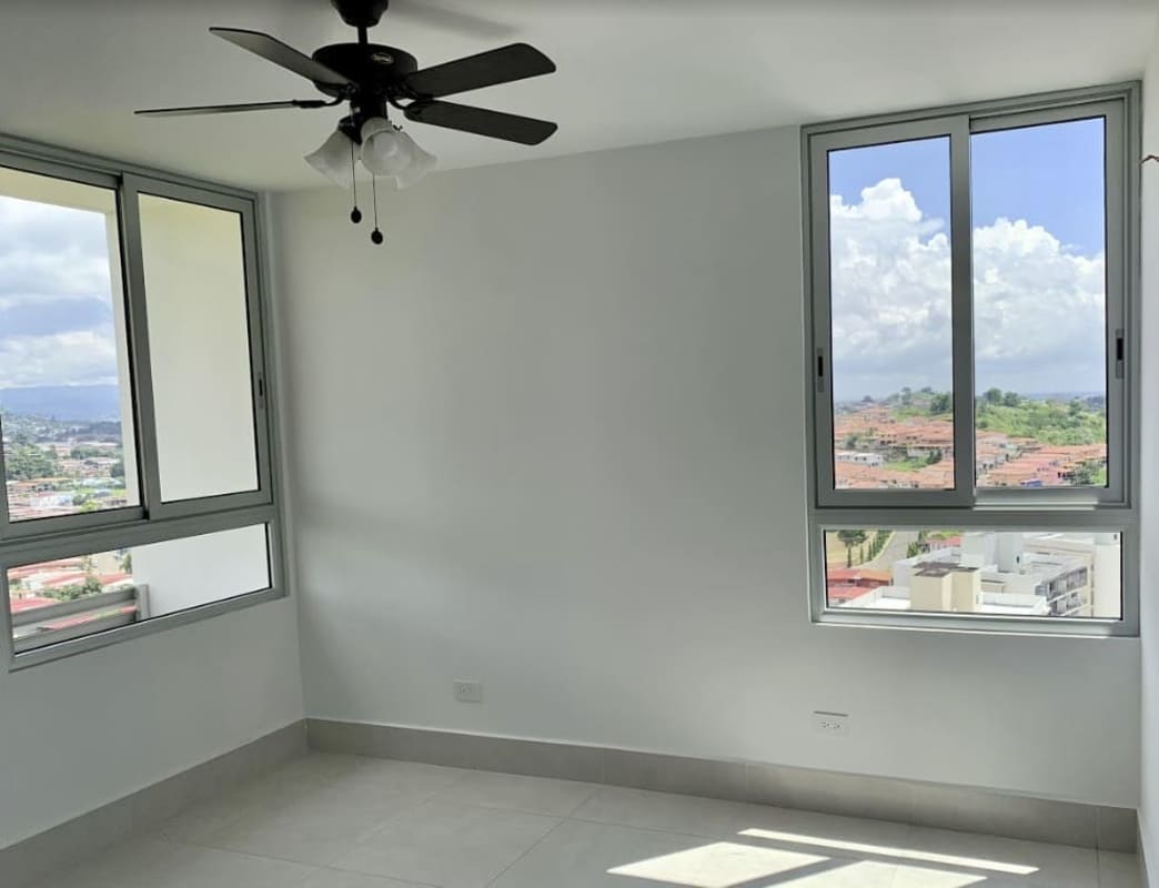 Bright empty bedroom with large windows, ceiling fan, tiled floor PH Green Wood