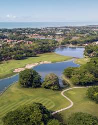 Aerial of golf course with lake and distant ocean in Buenaventura Panama