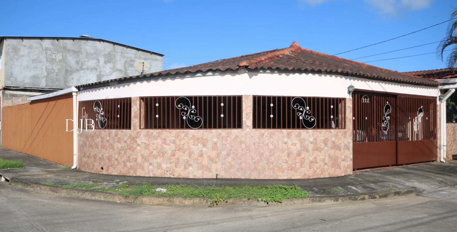 Corner lot house with tile roof, stone facade, iron windows, and garage gate, Pacora Panama