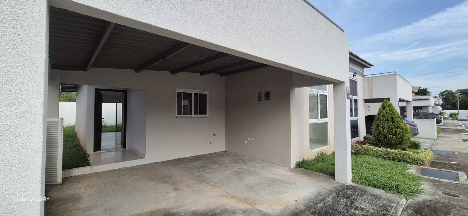 Covered parking area and minimalist modern facade with landscaped front garden in Costa Sur Panama