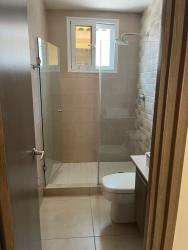 Modern bathroom with glass-enclosed shower, beige tiles and vanity in rental house Panama Pacifico