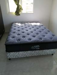 Bright bedroom with tufted grey mattress near window with natural light in Las Tablas apartment