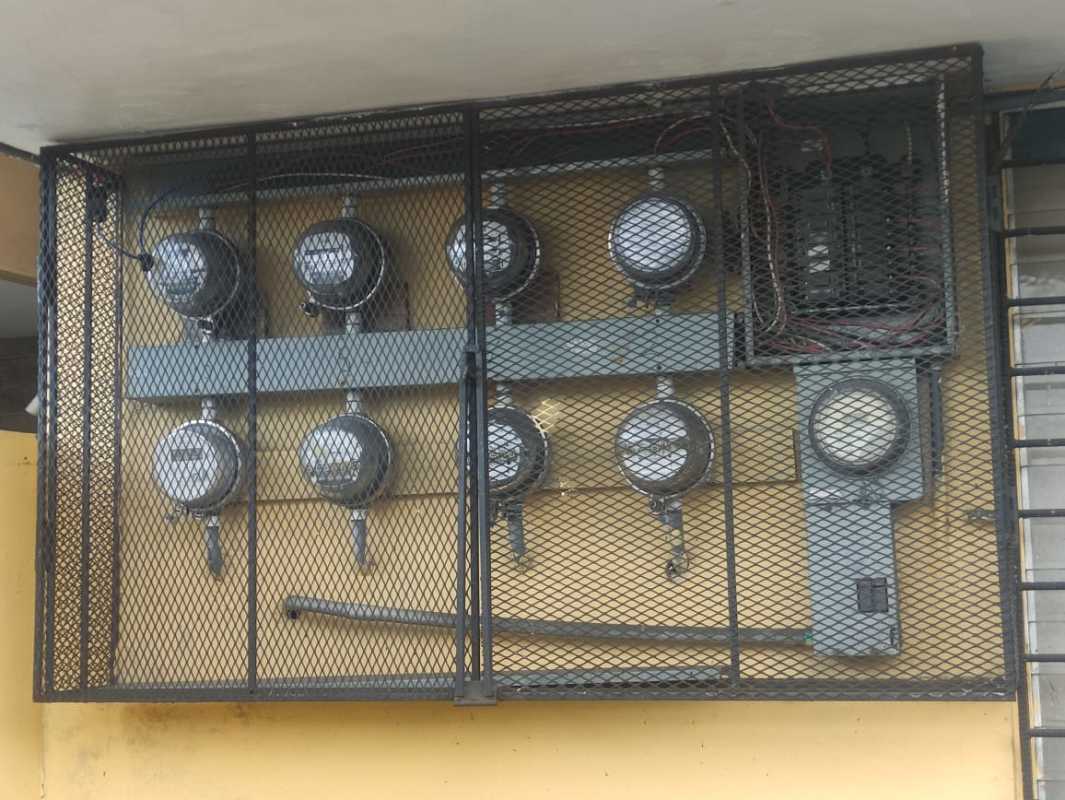 Group of electric meters enclosed in security cage outside apartment building in Panama City