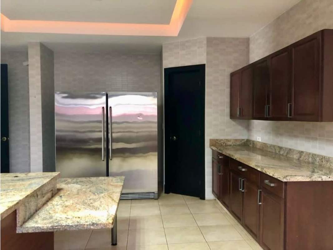 Swimming pool surrounded by palm trees, lawn and modern home facade Costa del Este Panama