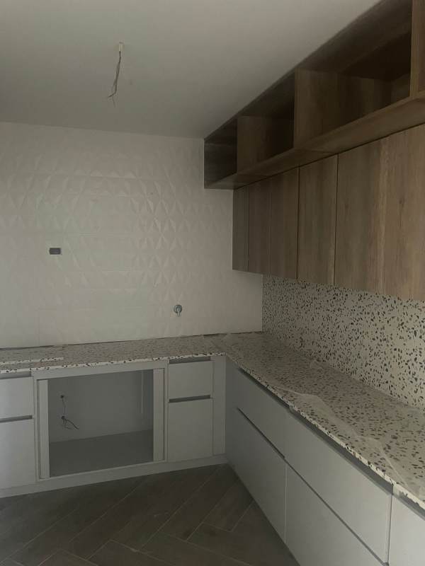 Kitchen with terrazzo counters, light wood cabinets, herringbone floor PH Brisa Marina Panama