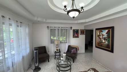Spacious living room with chandelier, tiled floors and tray ceiling in Las Tablas house