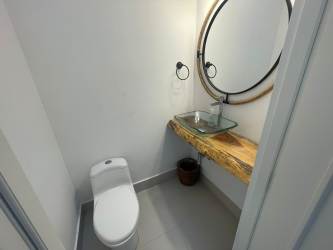 Elegant half bathroom with wood countertop and round mirror Punta Caelo Panama