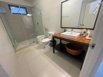 Spacious modern bathroom with glass shower, vessel sink on wood vanity Punta Caelo Panama