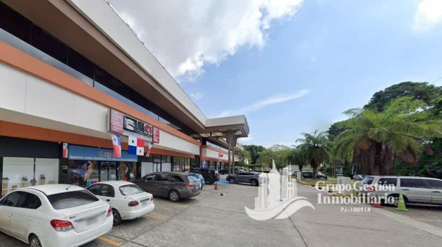 Two-story shopping plaza with signage, palm trees and parking area in Albrook Panama