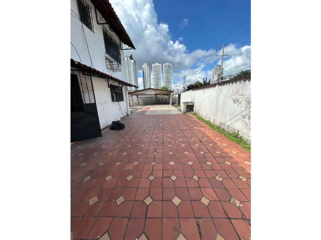 Large tiled patio with parking spaces, white facade, secure fencing and city skyline view in San Francisco Panama commercial house