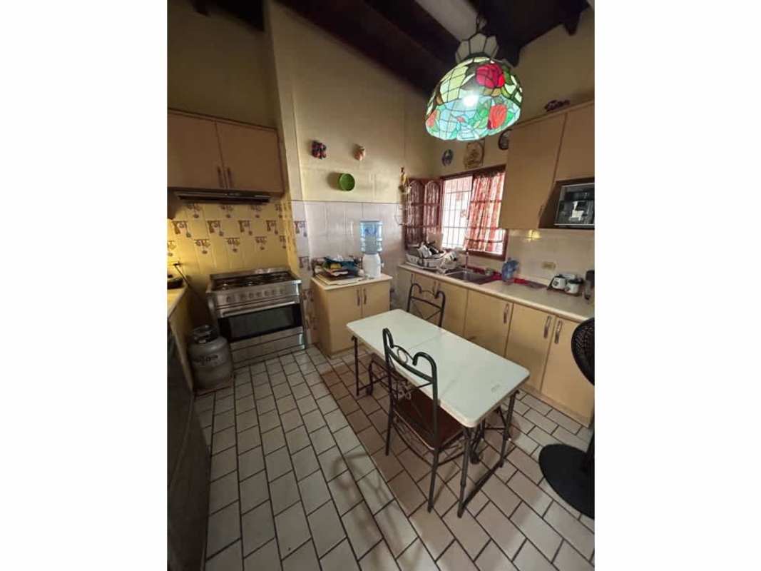 Traditional kitchen with wooden cabinets and tiled floors in Chanis family home for sale