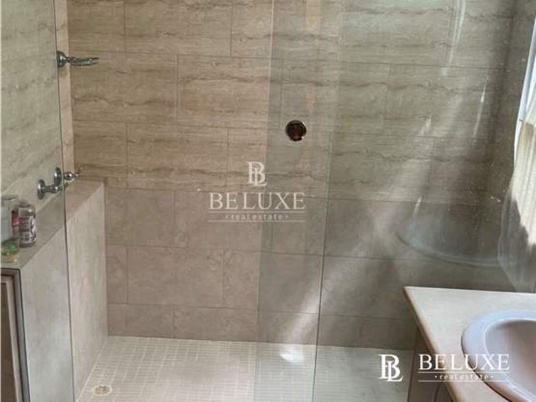 Bathroom with walk-in glass shower featuring beige natural stone tiles in PH Amador Hill Panama