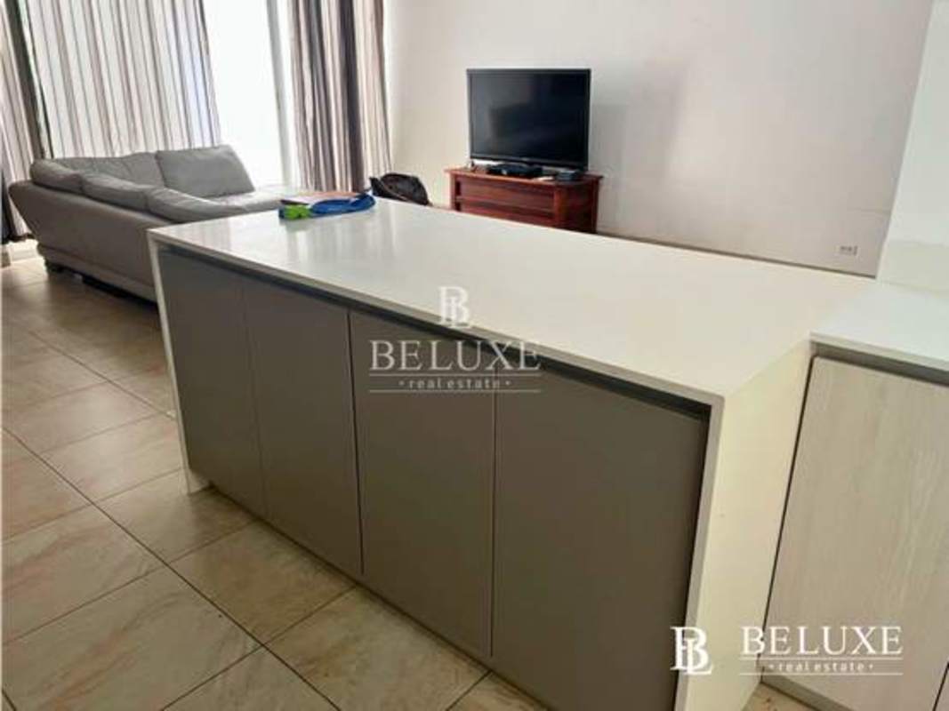 Modern open living area with kitchen island, gray sofa and flat-screen TV PH Amador Hill Panama