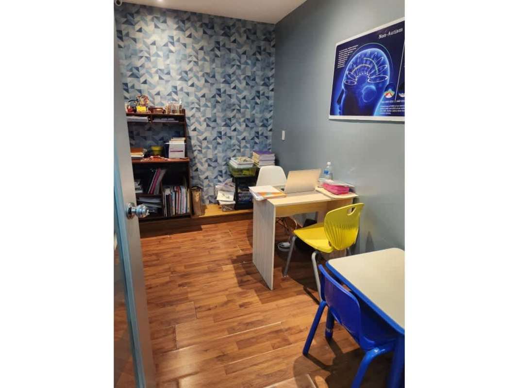 Small therapy study room with colorful accent wall bookshelf and kids chairs in commercial daycare facility Panama City