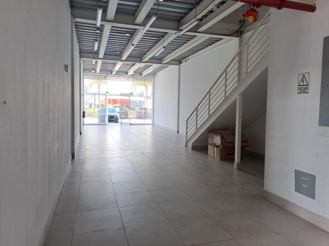 Glass door entrance with tiled floors metal staircase open plan showroom Plaza Llano Bonito Panama City