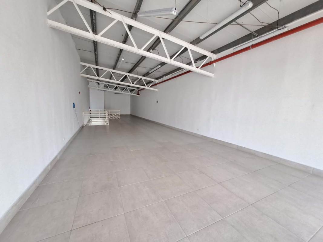 Open commercial loft space with metal trusses tiled floors storefront windows Plaza Llano Bonito Panama City