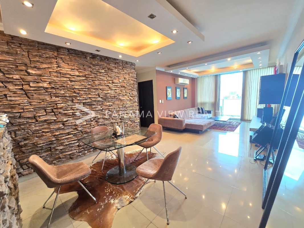 Dining space with glass table, upholstered chairs, stone accent wall PH Pacific Sun Punta Pacífica