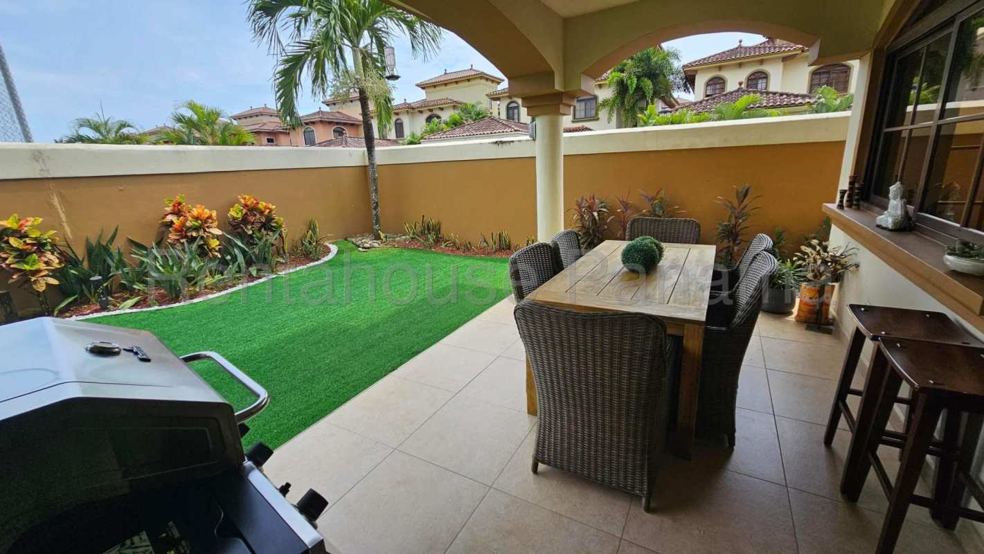 Covered terrace with dining and barbecue area overlooking garden in Costa Sur Panama